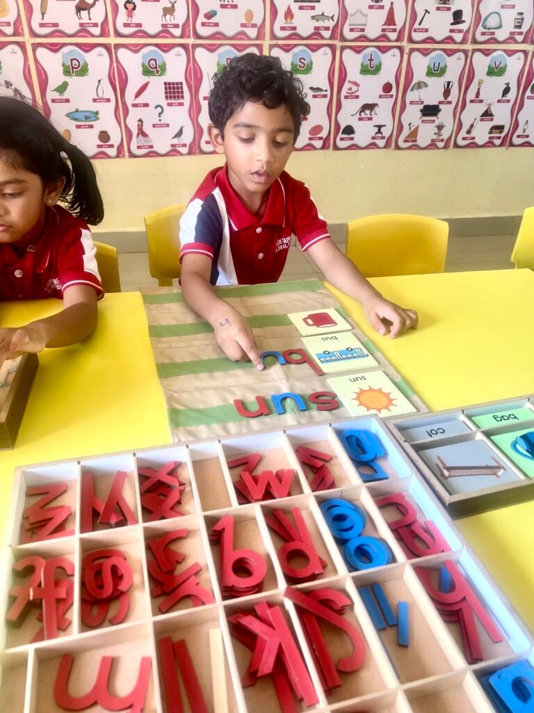 Boy learning letters with wooden alphabet blocks and cards at yellow table at one of the best schools in Miyapur.