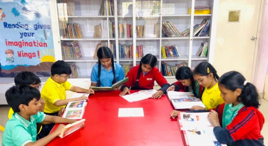 Group of students reading books together around a table in a library at one of the best schools in Kukatpally.
